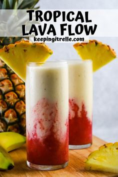 two glasses filled with red and white liquid next to sliced pineapple