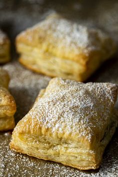 several pastries are sitting on a table covered in powdered sugar and sprinkled with icing