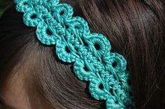 a close up of a woman's head wearing a green crochet hair band