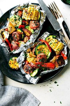 a person is holding a fork over some foil with vegetables on it and other food in the background