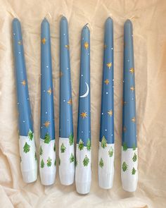 four blue and white candles with christmas trees painted on them are lined up next to each other