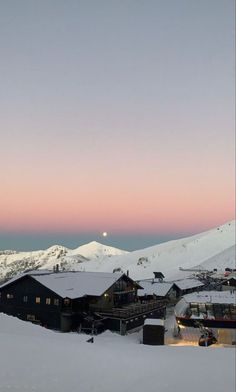 the sky is pink and purple as the sun sets in the mountains behind it, with snow on the ground