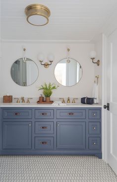 a bathroom with two sinks and mirrors on the wall, along with a potted plant