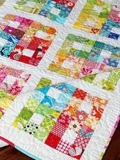 a multicolored patchwork quilt on a wooden floor