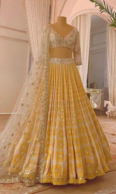 a yellow lehenga is displayed on a mannequin in front of a window