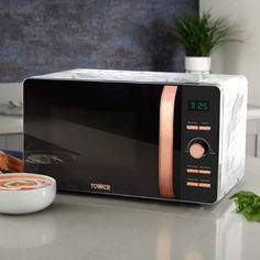 a black microwave oven sitting on top of a counter next to a bowl of food