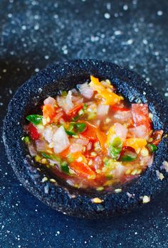 a small black bowl filled with food on top of a blue tablecloth covered in confetti and sprinkles