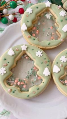 four decorated cookies sitting on top of a white plate next to candy canes and christmas decorations