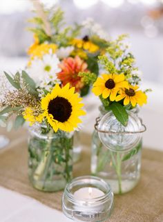 sunflowers and other flowers are in mason jars on a table with burlocks