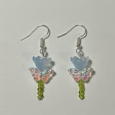 a pair of earrings with blue and pink flowers on them, sitting on a white surface