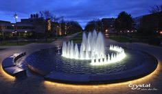 an illuminated fountain in the middle of a park