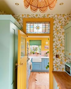 a yellow and blue kitchen with lots of light coming in from the window over the sink