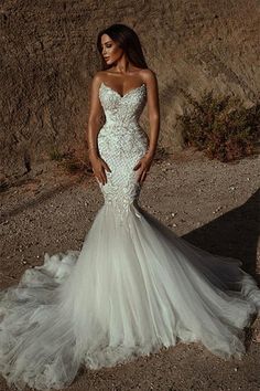 a woman standing in front of a mountain wearing a wedding dress