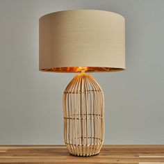 a lamp that is sitting on top of a wooden table with a white shade over it