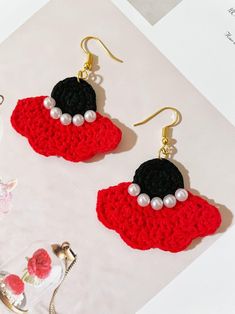 two crocheted earrings with pearls on them sitting next to a tea pot and cup