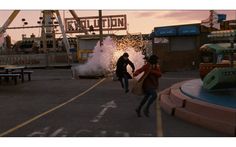 two people are running across the street carrying surfboards in front of an amusement park