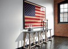 an american flag is hanging on the wall next to a table with candles in front of it