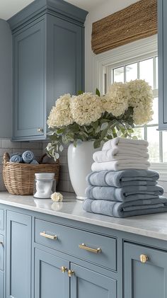 towels and flowers in a white vase on a blue kitchen counter with gold hardware pulls