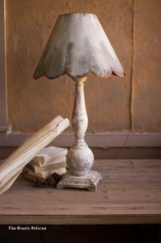 a lamp sitting on top of a wooden table next to a pile of books and a piece of wood