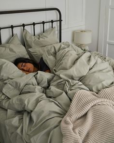 a woman laying in bed under a blanket