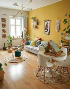 a living room filled with furniture and lots of plants on top of wooden flooring