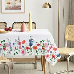 a table with flowers and fruit on it in front of a painting hanging on the wall