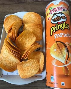 a can of pringles next to some pastries on a plate with chips