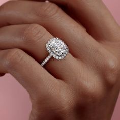 a woman's hand holding an engagement ring with a diamond on the middle and side