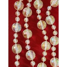 the beads have been made out of glass and are hanging on a red fabric background