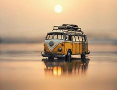 a yellow and white bus is sitting on the water with its surfboard strapped to it's roof