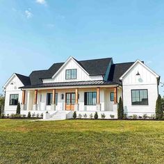 a white house in the middle of a field with grass and bushes on both sides