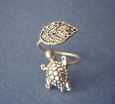 a silver ring with a turtle on it's back and a leaf on top