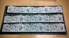 three pieces of white lace sitting on top of a wooden table next to each other