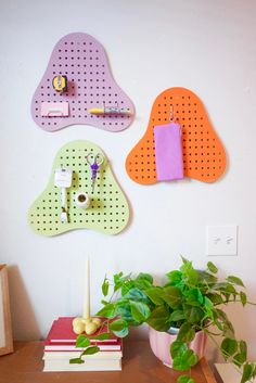 there are three pegs on the wall to hold magnets and pens, along with a potted plant