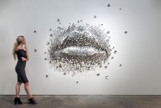 a woman is walking past a sculpture with butterflies on it's face and mouth