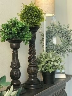 three potted plants are sitting on top of a mantle in front of a mirror