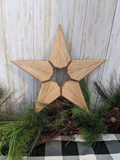 a wooden star sitting on top of a table next to pine cones and greenery