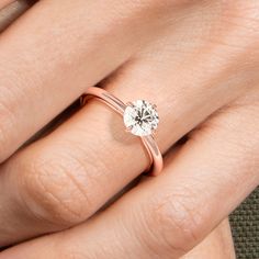 a woman's hand with a rose gold ring and a white diamond in it