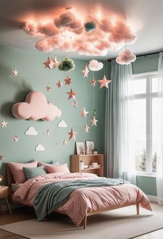 a bedroom decorated in pastel colors with stars and clouds hanging from the ceiling above the bed