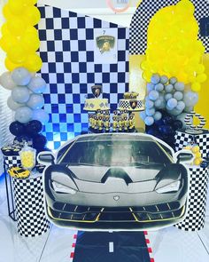 a black and white car is on display in front of some yellow and blue balloons