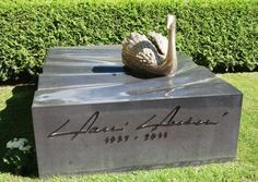 a statue of a swan on top of a box in the middle of some grass