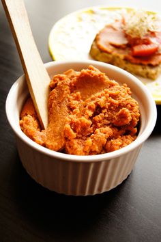 a bowl of food with a wooden spoon in it on a table next to another plate