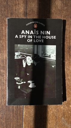 the book anai nin is on top of a wooden table next to a cup and saucer