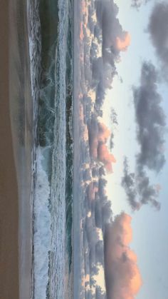 an aerial view of the beach and ocean with clouds in the sky, as seen from above