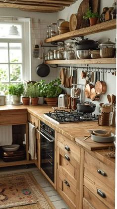 a kitchen filled with lots of wooden cabinets and counter top covered in pots and pans