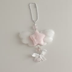 a necklace with angel wings and a pink bow hanging from it's side on a beaded chain