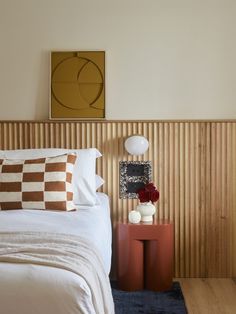 a bed with white and brown pillows on top of it next to a wooden wall