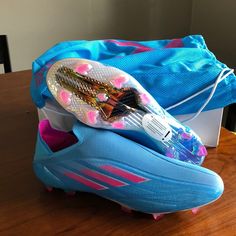 a pair of blue and pink soccer cleats sitting on top of a wooden table