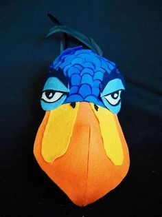 a close up of a stuffed animal on a black surface with blue and orange feathers