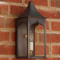 a wall mounted light on the side of a brick building with a candle in it